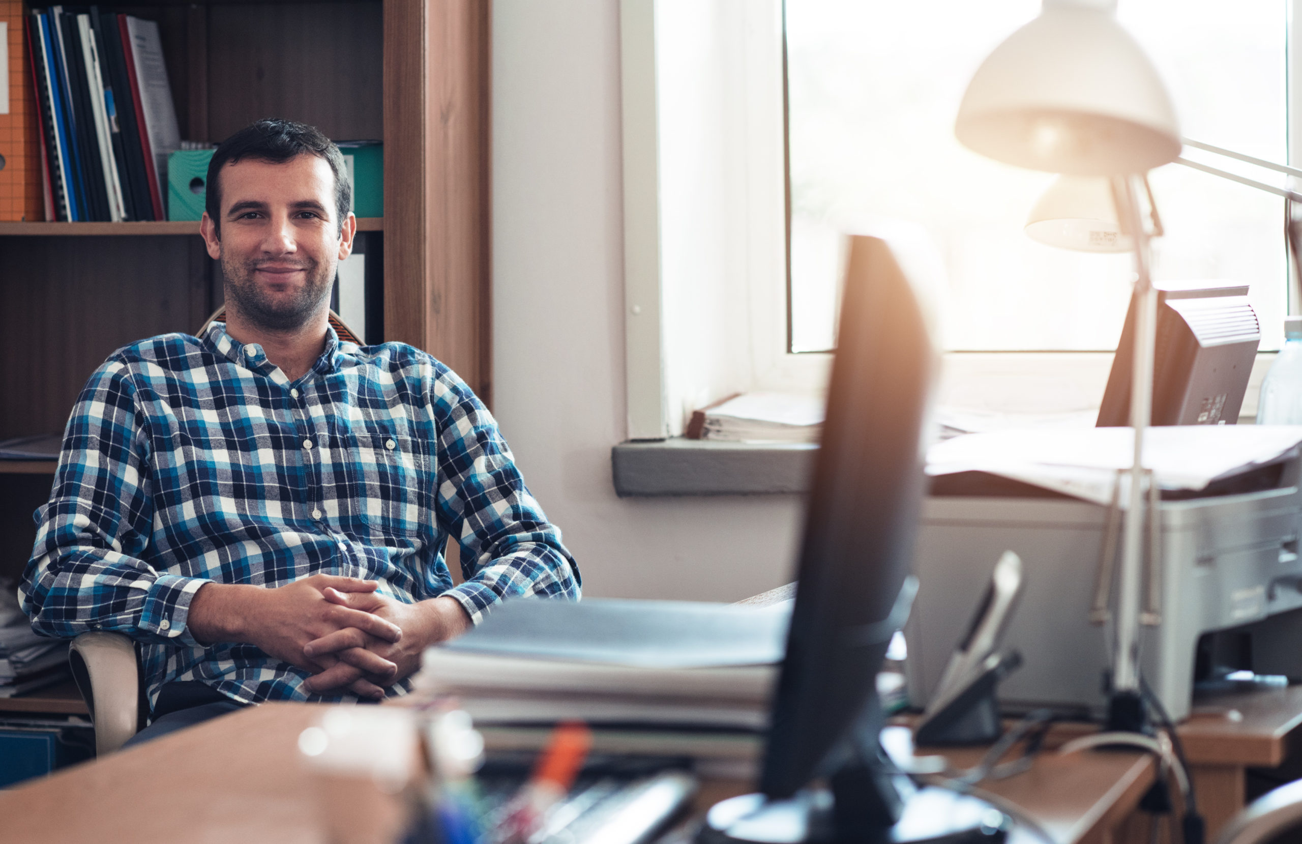 Smiling,Young,Businessman,Sitting,In,A,Bright,Office